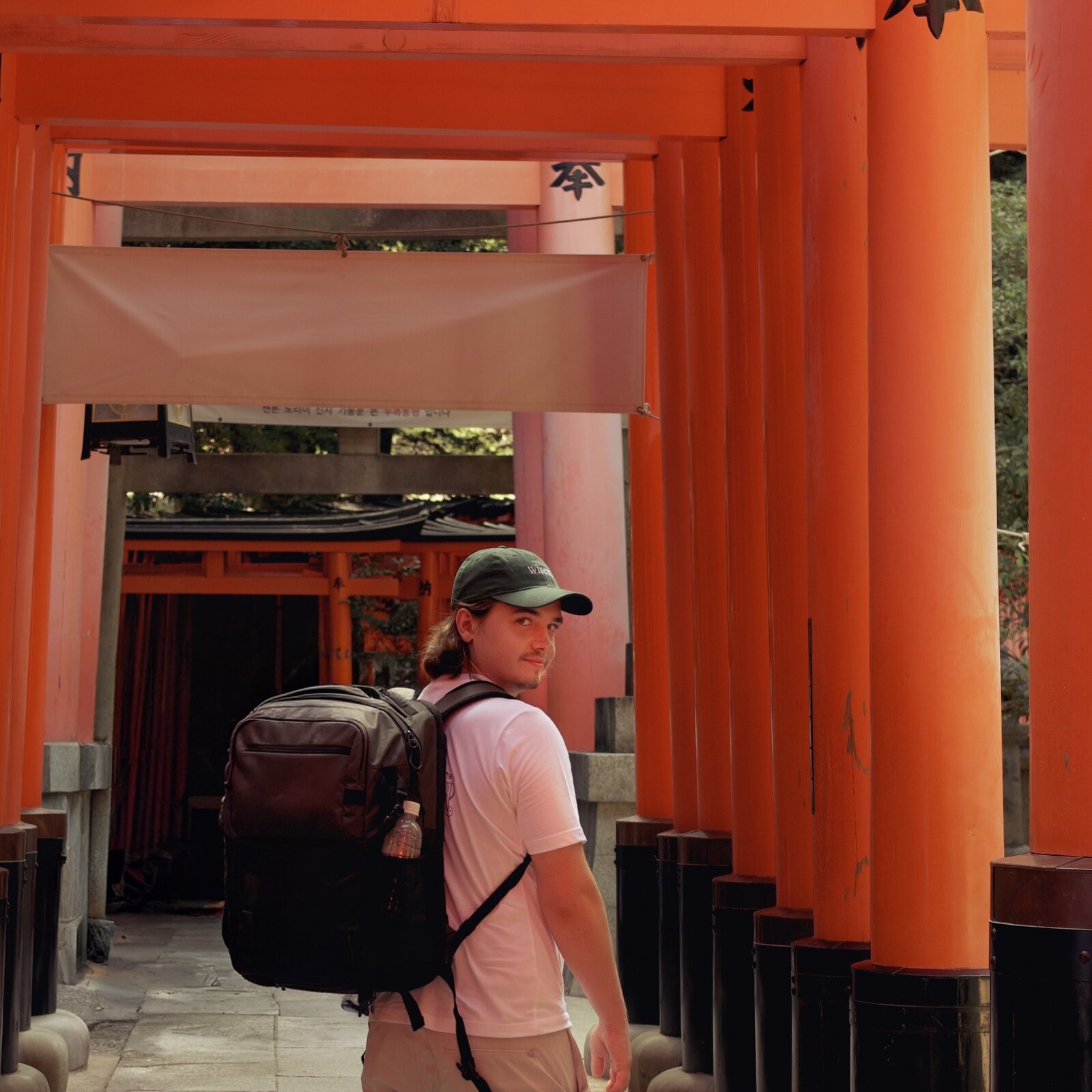 Jakub Towarek standing among red torii gates at Fushimi Inari in Kyoto